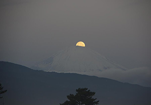 月が富士山に半分かくれたところ